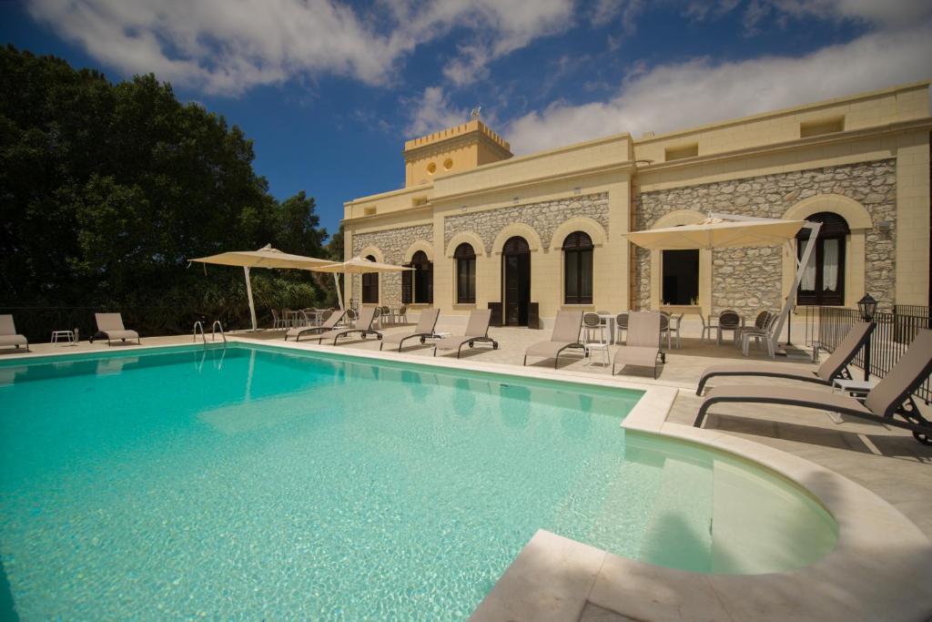 特拉帕尼Villa le Torri B&B的一座带椅子的游泳池以及一座建筑