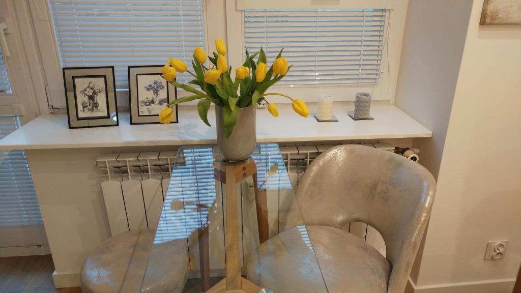 奥古斯图Apartament Centrum的黄花花花瓶,放在桌子上,椅子