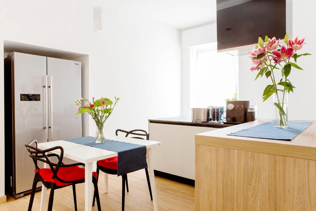 维罗纳B&B agli Orti的一间带一张桌子和两把椅子的厨房和一间带白色橱柜的厨房