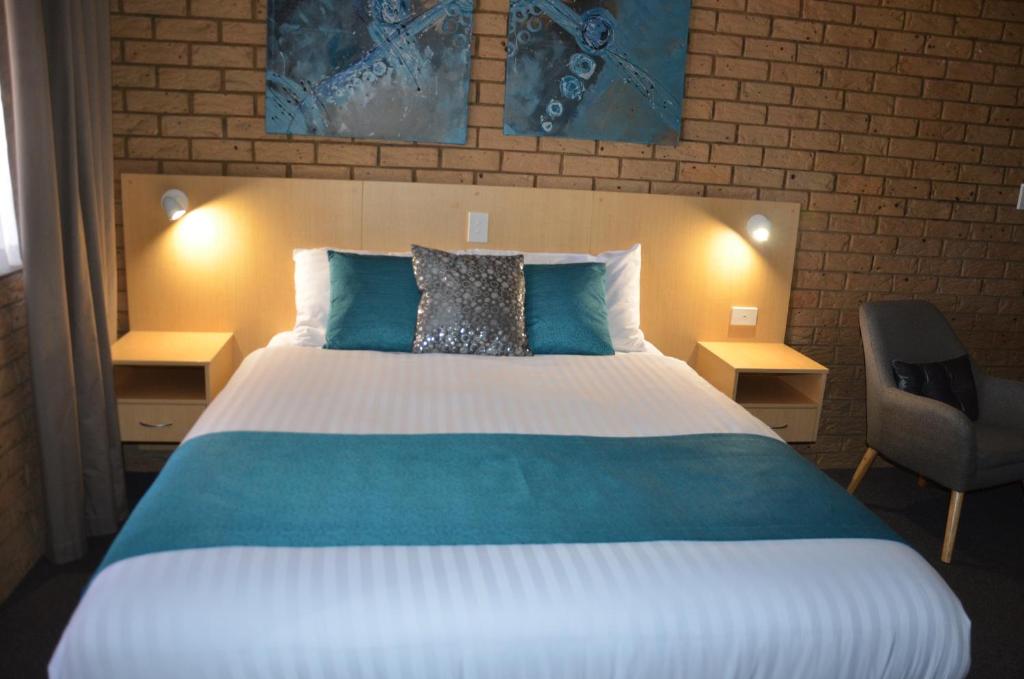 土乌巴阳光汽车旅馆的一间卧室配有一张大床和一把椅子