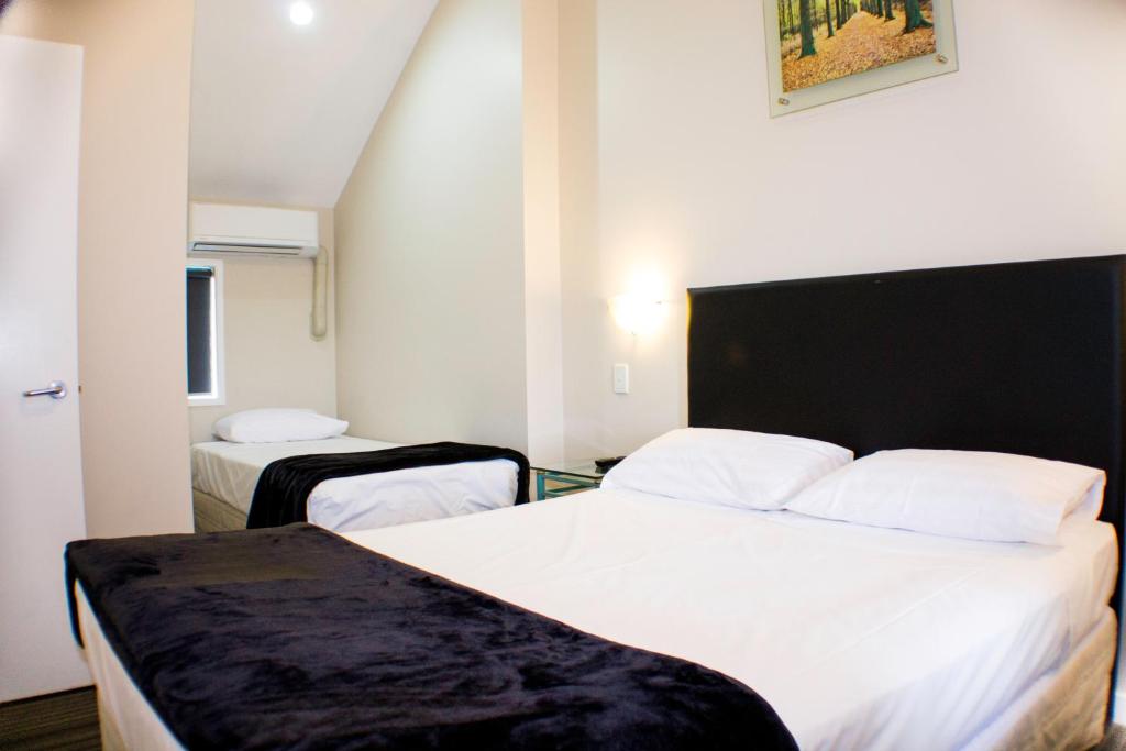 奥克兰瑞兰汽车旅馆的酒店客房,配有两张带白色床单的床