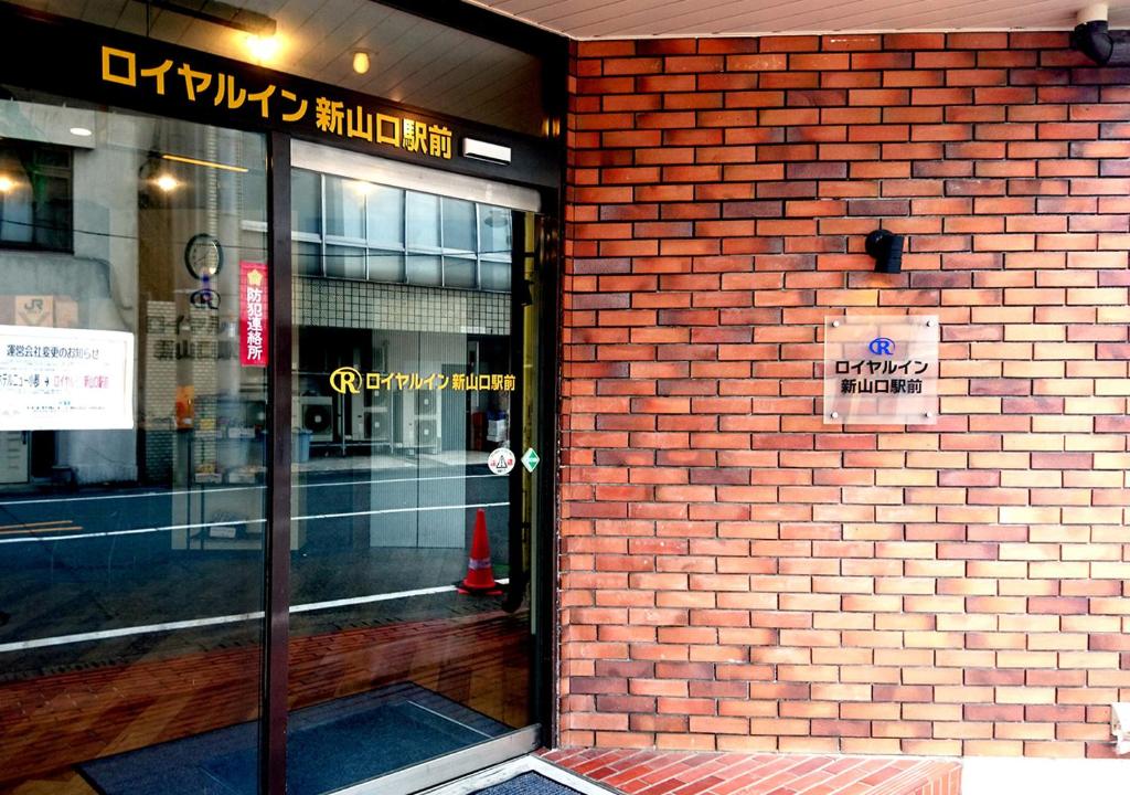 山口Royal Inn Shinyamaguchi Ekimae的商店的砖墙,门上标有标志