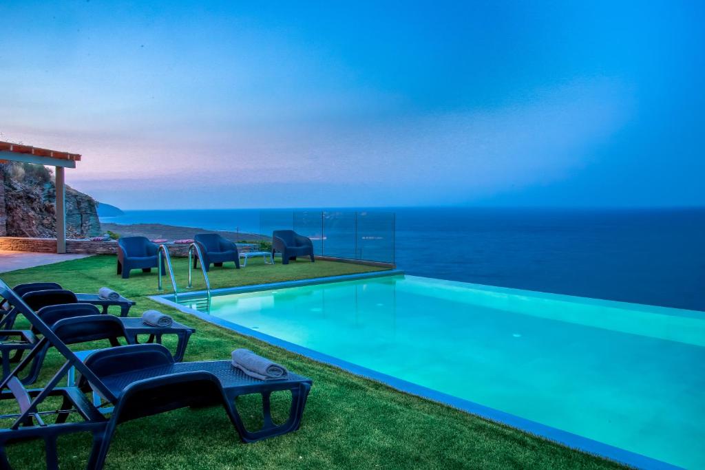 SinétionAnastasis Luxury Villa Andros With Heated Pool的一个带椅子的游泳池,背景是大海