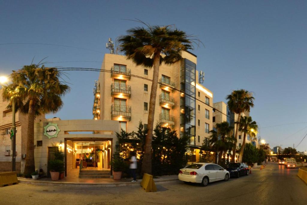 安曼Guest House Hotel Amman by FHM的街道前方有棕榈树的建筑