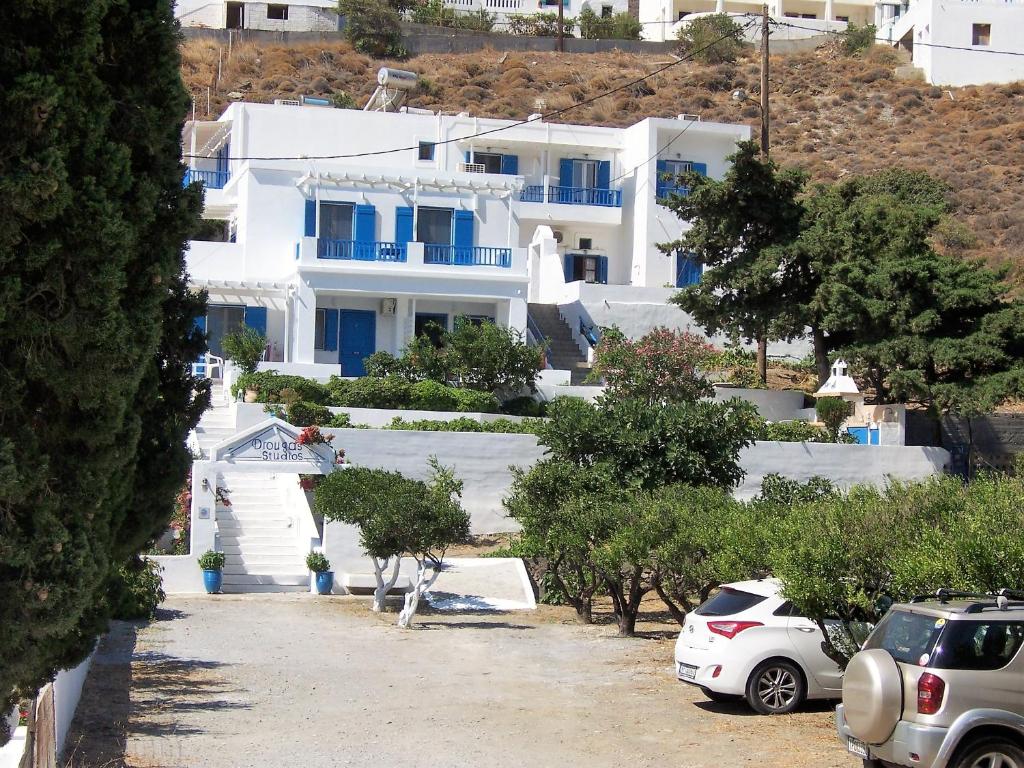 Livadi AstypalaiasDrouga's Studios & Suites Astypalaia Greece的一座白色的大建筑,前面有汽车停放