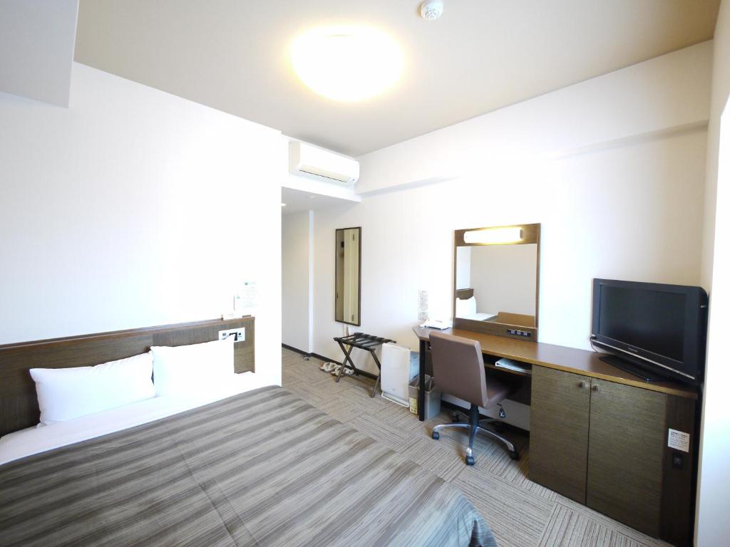 彦根市鲁特酒店-彦根旅馆的酒店客房配有一张床、一张书桌和一台电视。