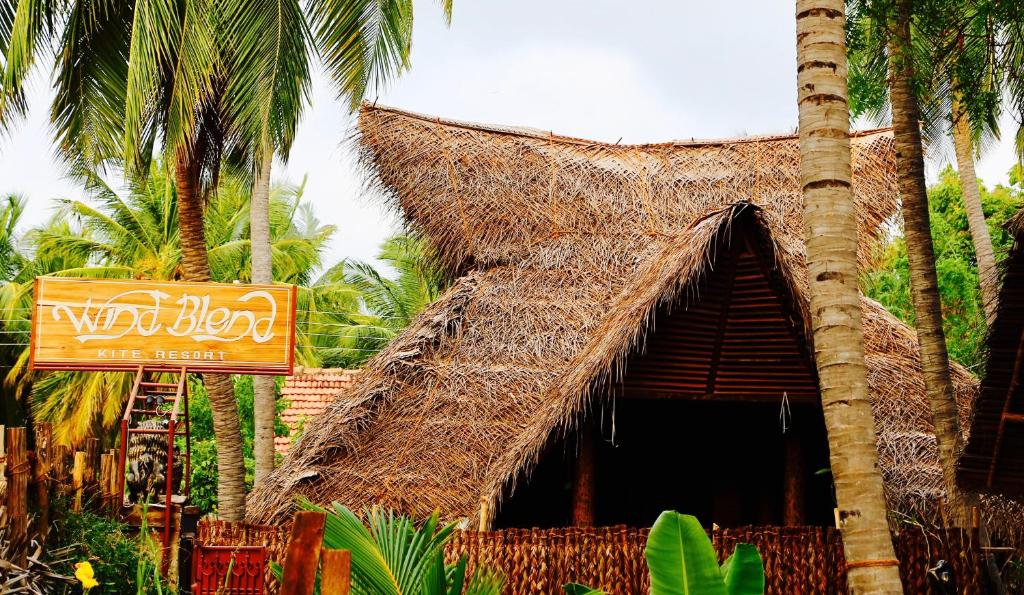 卡尔皮蒂耶Wind Blend Kite Resort的一间拥有稻草标志和棕榈树的餐厅