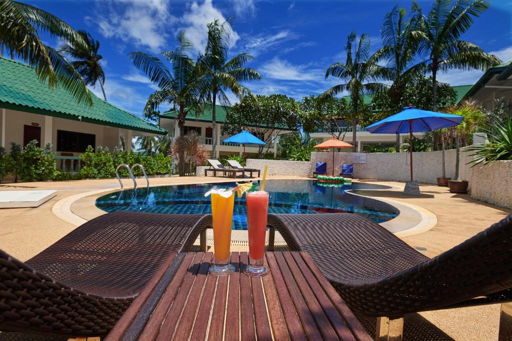 拉迈苏梅岛珊瑚礁景观度假酒店的池畔木桌旁的2杯饮料