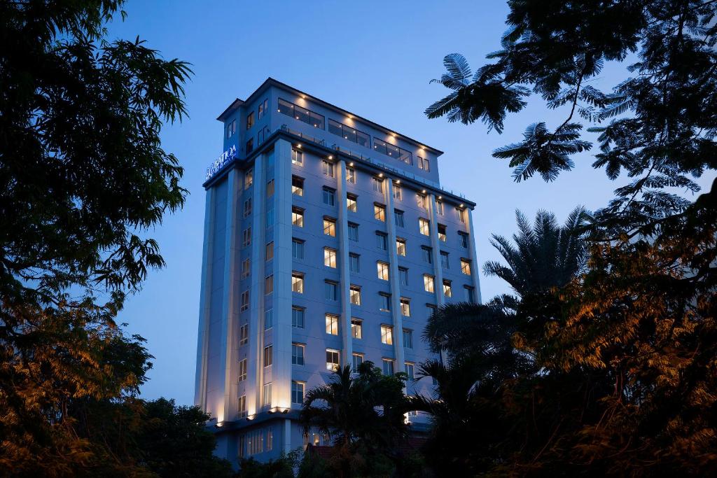 泗水BATIQA Hotel Darmo - Surabaya的一座高大的建筑,晚上有灯