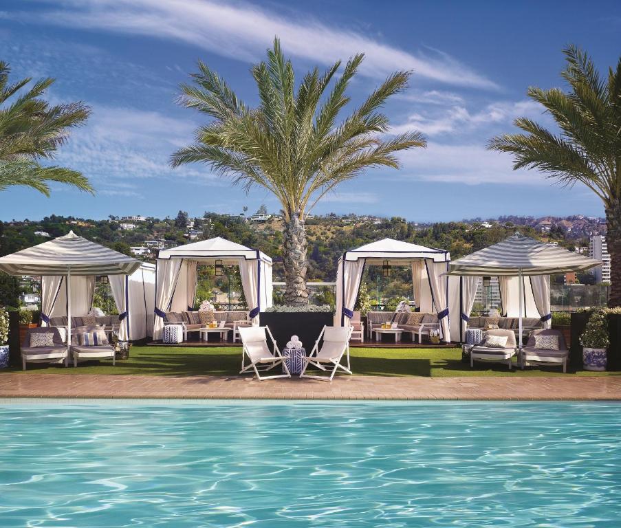 洛杉矶比佛利山庄伦敦西好莱坞酒店的一个带椅子的度假村和一个棕榈树游泳池
