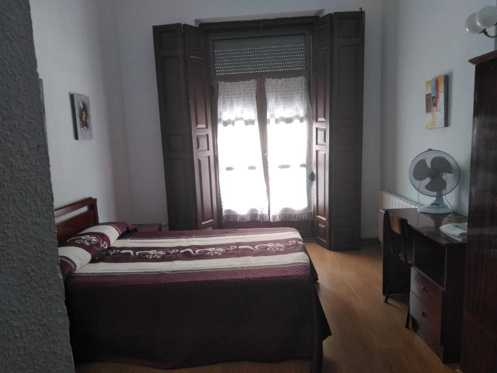 卡塞雷斯Pension Carretero的一间卧室配有一张床、一个梳妆台和一扇窗户。