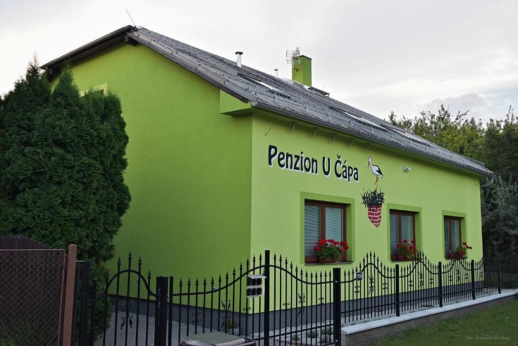 普日博尔Penzion u Čápa Příbor的黄色和绿色的建筑,有黑色的栅栏