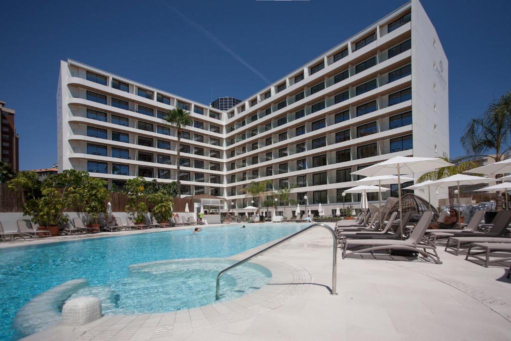 贝尼多姆Hotel Presidente 4 sup的酒店游泳池的背景是一座大型建筑