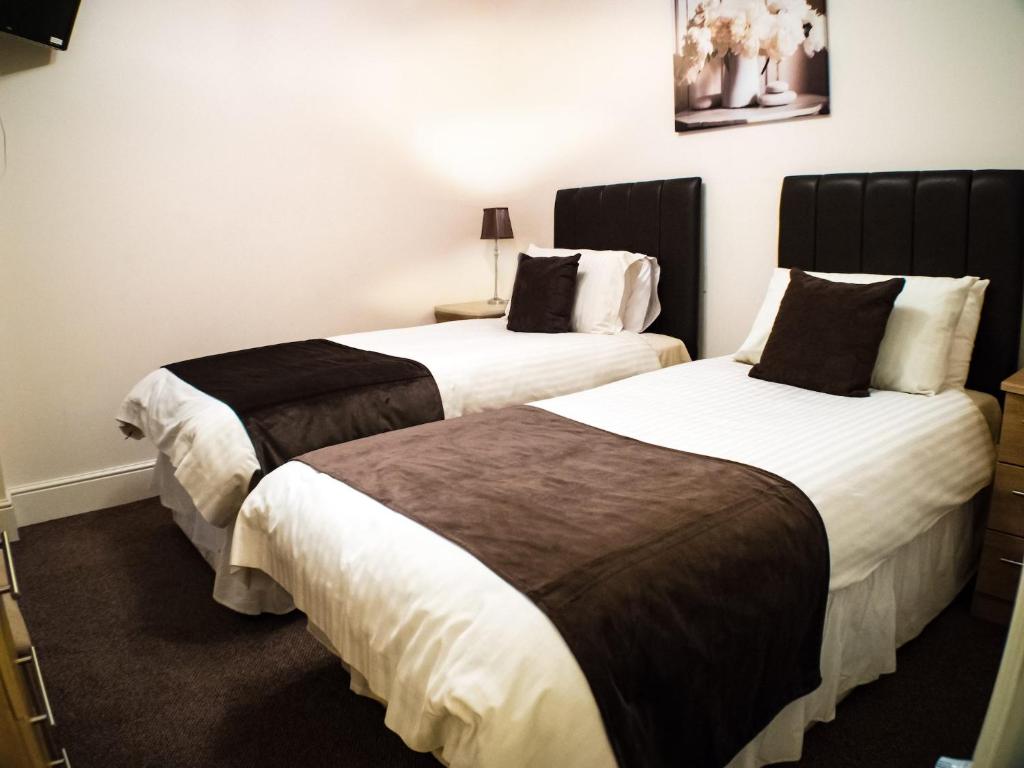 道格拉斯梅勒塞德酒店的配有2张位于酒店客房的床,配有白色和棕色床单