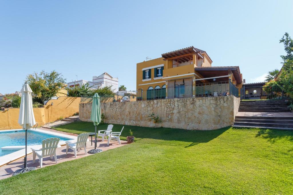 桑卢卡尔-德巴拉梅达Bonito Chalet Con Vistas的一座带游泳池的房子和一个带椅子和遮阳伞的庭院