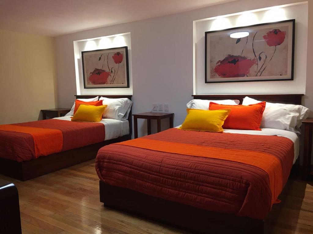 圣路易斯波托西圣露西亚博斯克酒店的客房 - 带两张带橙色和黄色枕头的床