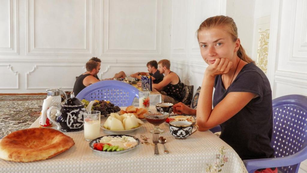 布哈拉Diyor Hostel的坐在餐桌上吃一盘食物的女人