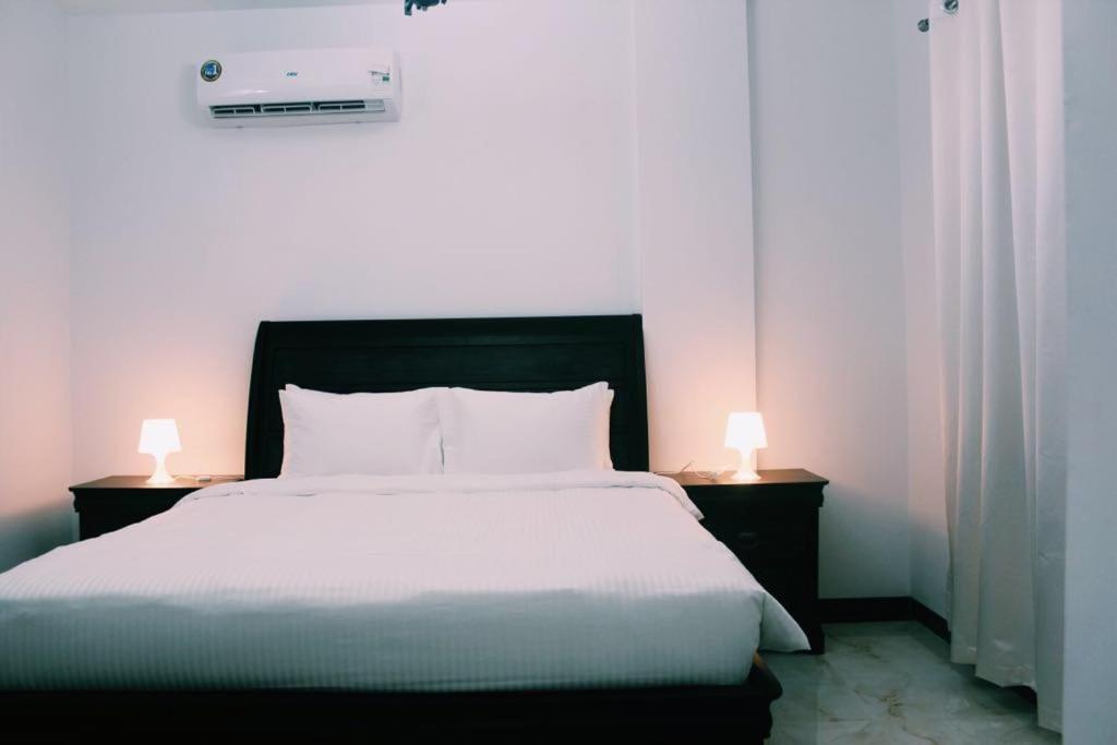 MūkhīAlhama Hotel Appartment的一间卧室配有一张大床,桌子上放着两盏灯