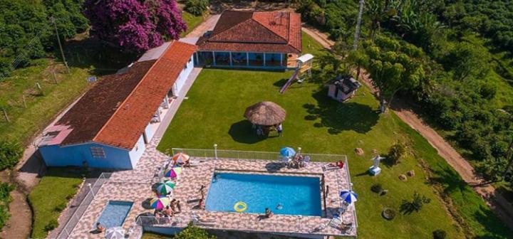 塞拉内格拉Pousada Primavera da Serra的享有带游泳池的房屋的空中景致
