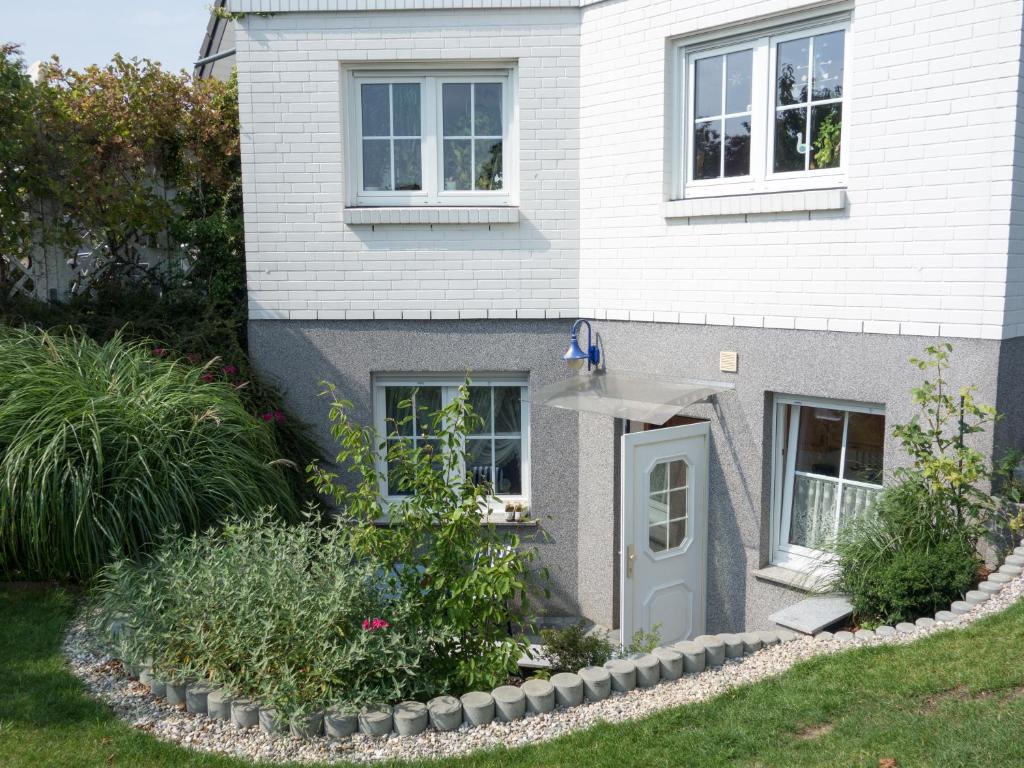 巴特多布兰Ferienwohnung Holunderweg的白色的房子,有蓝色的门和一些植物