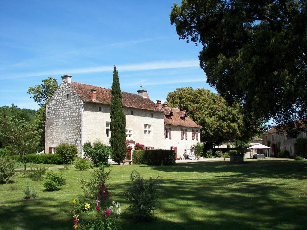 Saint-Jean-de-ThuracDomaine du Noble的一座大型石头建筑,有树庭院