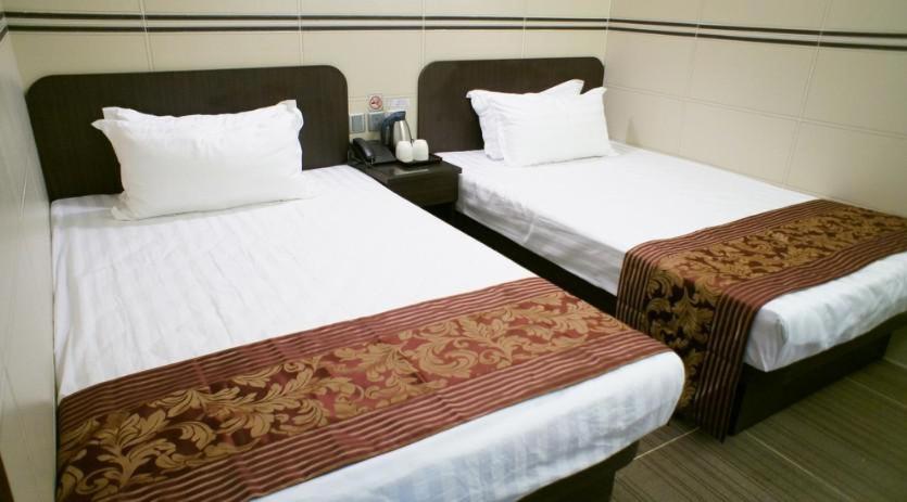 香港比比旺角宾馆的配有白色床单的酒店客房内的两张床