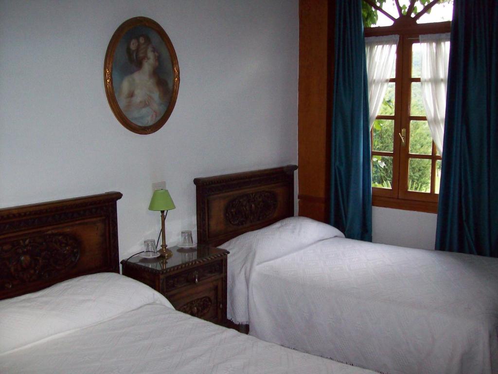 CasoHotel Rural La Lastra的一间卧室设有两张床,墙上设有一面镜子