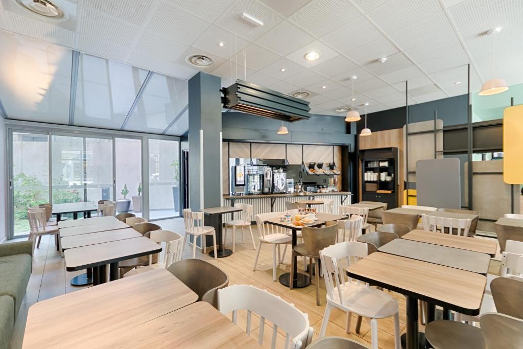 马赛B&B HOTEL Marseille Centre La Joliette的配有木桌和白色椅子的餐厅
