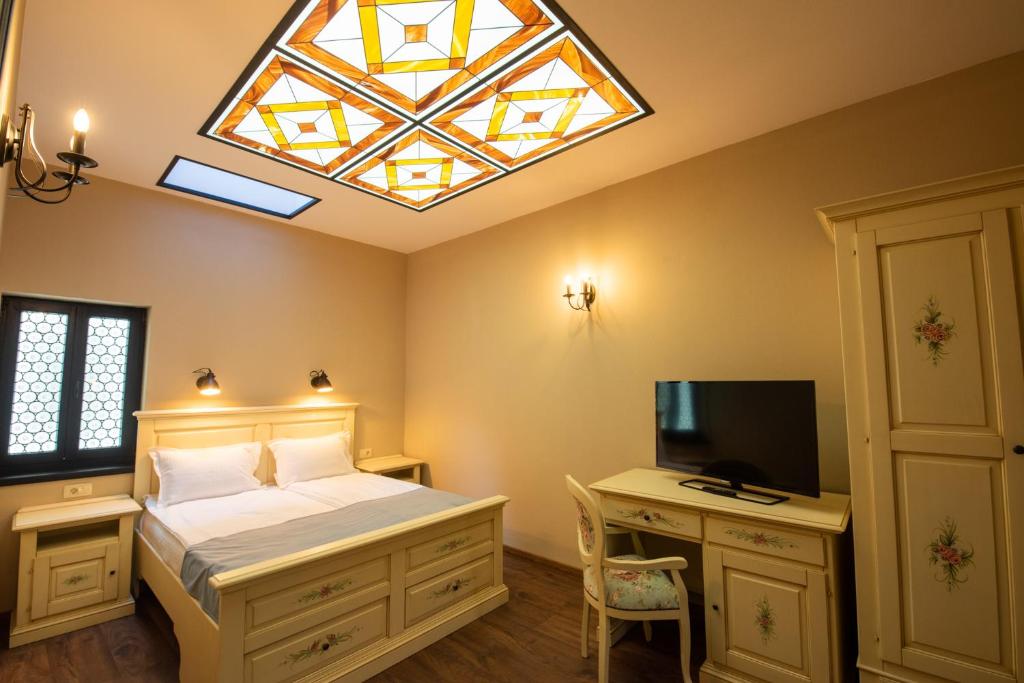 布拉索夫HOTEL BOUTIQUE CASA CHITIC -HOTEL AND RESTAURANT Str Johann Gott nr7的一间卧室设有一张床、一台电视和一个窗口。