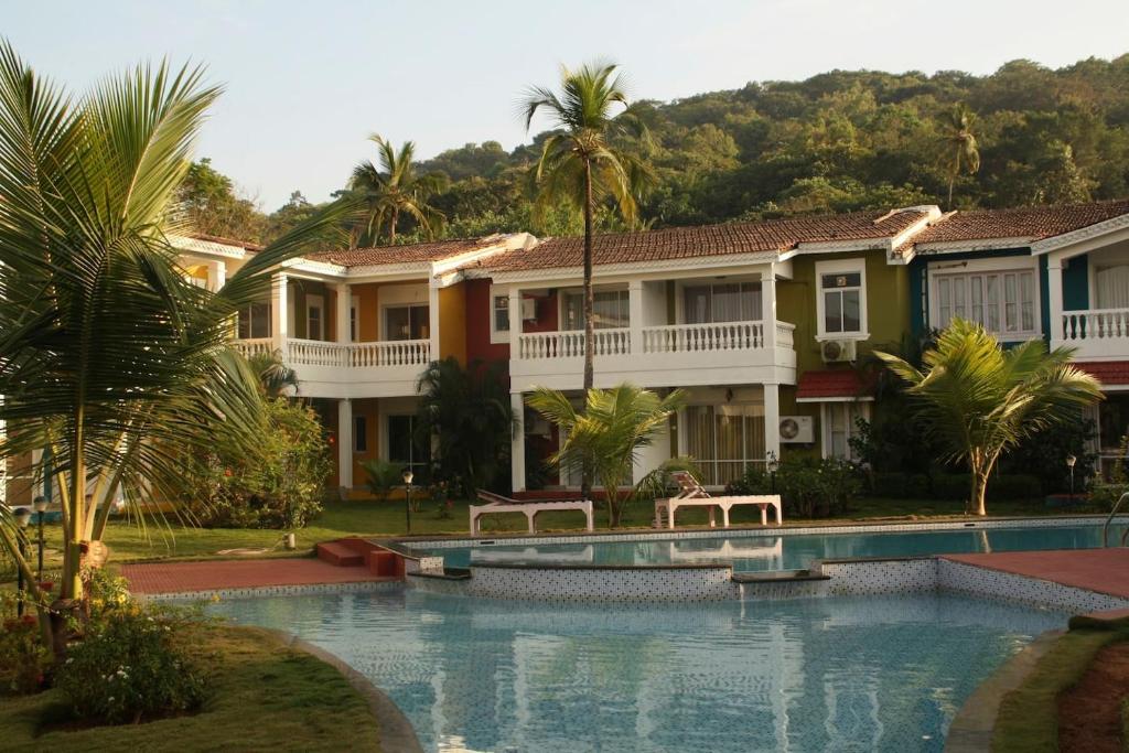 西奥利姆Riverside Villa at Siolim的一座带游泳池和棕榈树的房子