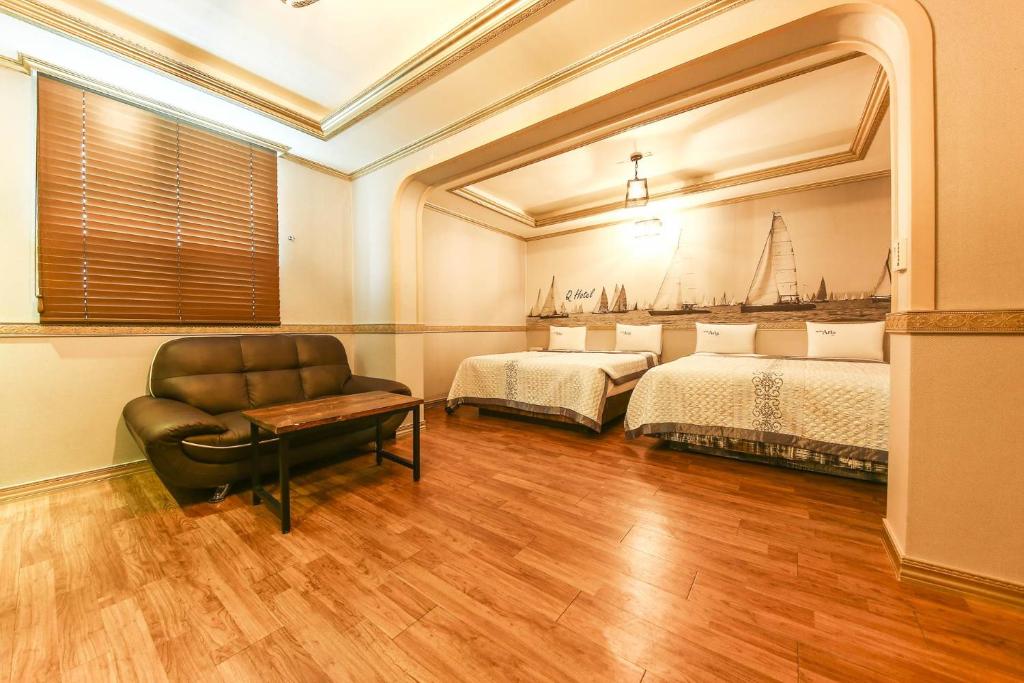 龙仁市龙仁Q酒店的一间设有两张床、椅子和镜子的房间