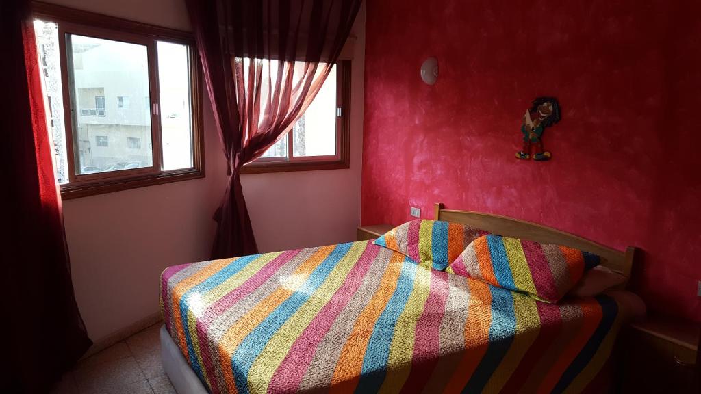 高尔夫德尔苏尔Habitaciones Javi Los Abrigos的一间卧室配有一张带五颜六色的被子的床和窗户