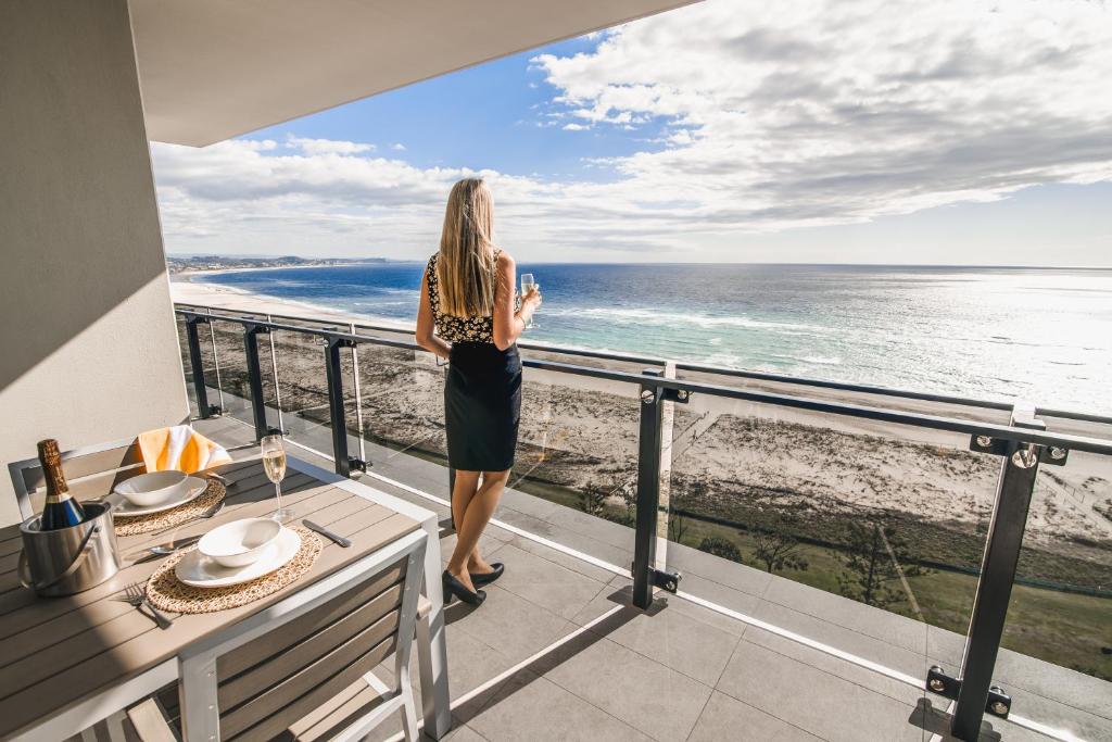 黄金海岸基拉海滩地标度假酒店的站在一个眺望海洋的阳台上的女人