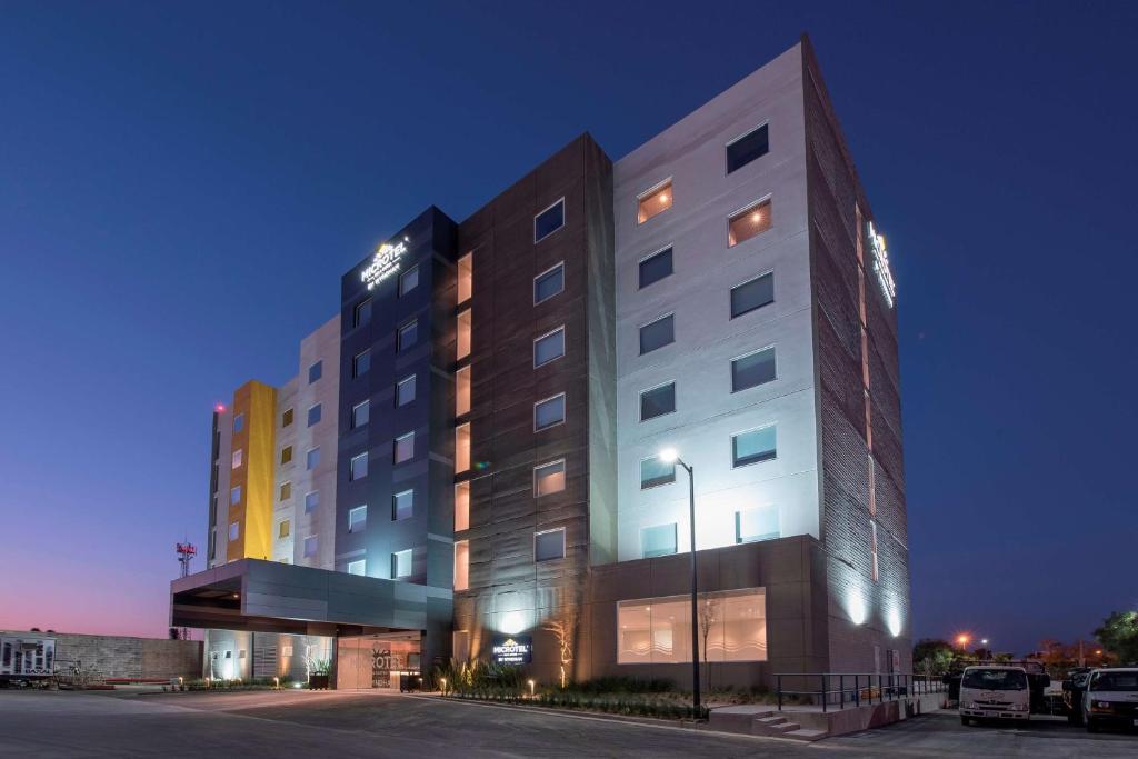 圣路易斯波托西Microtel Inn & Suites by Wyndham San Luis Potosi的一座有照明的建筑,前面有一个停车位