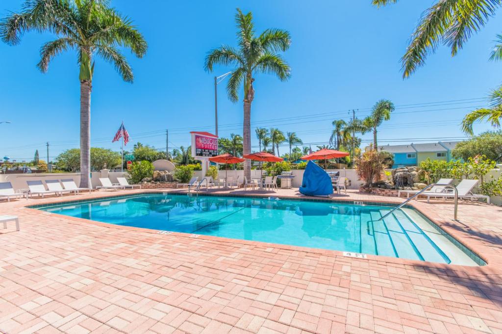 萨拉索塔萨拉索塔木槿套房汽车旅馆的一座棕榈树和遮阳伞的游泳池