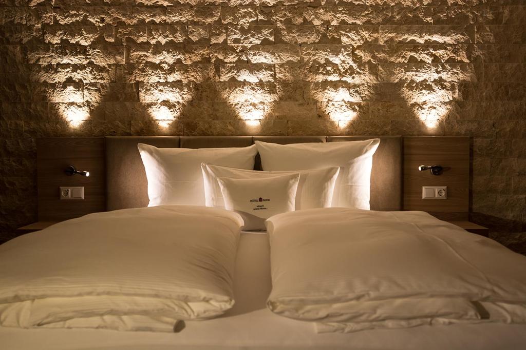 霍恩贝格Hotelmyhome的一张带白色枕头的床和一堵带灯光的墙壁