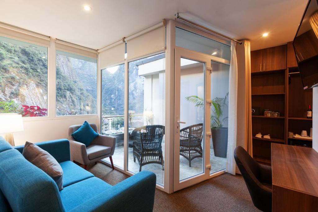 马丘比丘Inti Punku Machupicchu Hotel & Suites的客厅配有蓝色的沙发和椅子