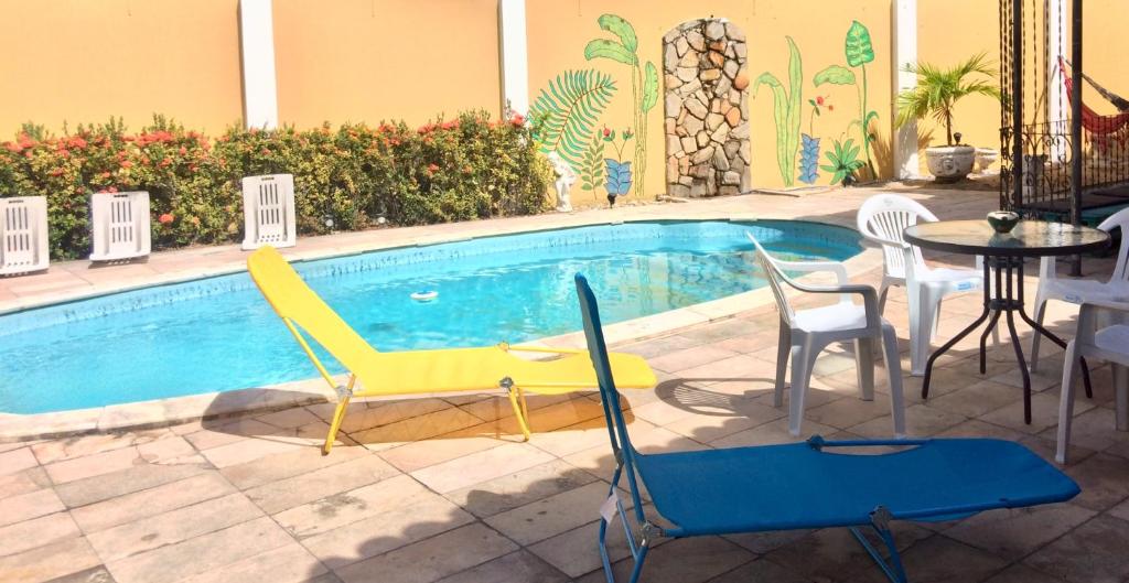 马塞约Hostel Morais Praia的游泳池配有桌椅和桌椅