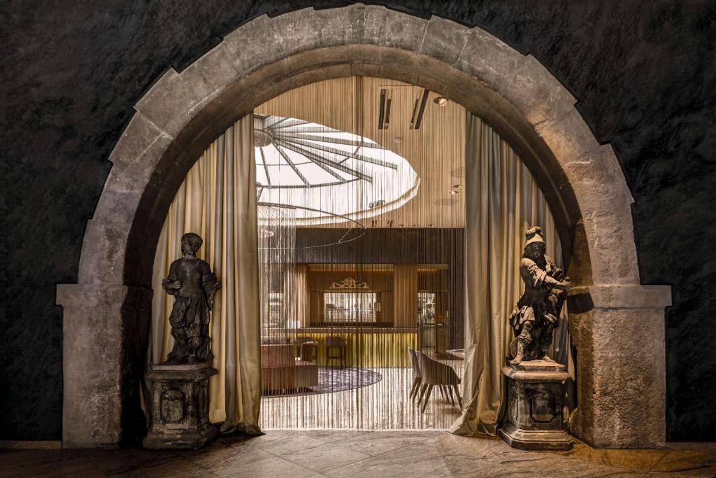 维尔茨堡雷布斯托克贝斯特韦斯特高级酒店的走廊上设有拱门,配有雨伞和两座雕像