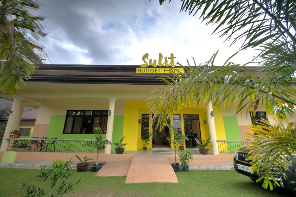 杜马格特Sulit Budget Hotel near Dgte Airport Citimall的黄色和绿色的建筑,上面有标志