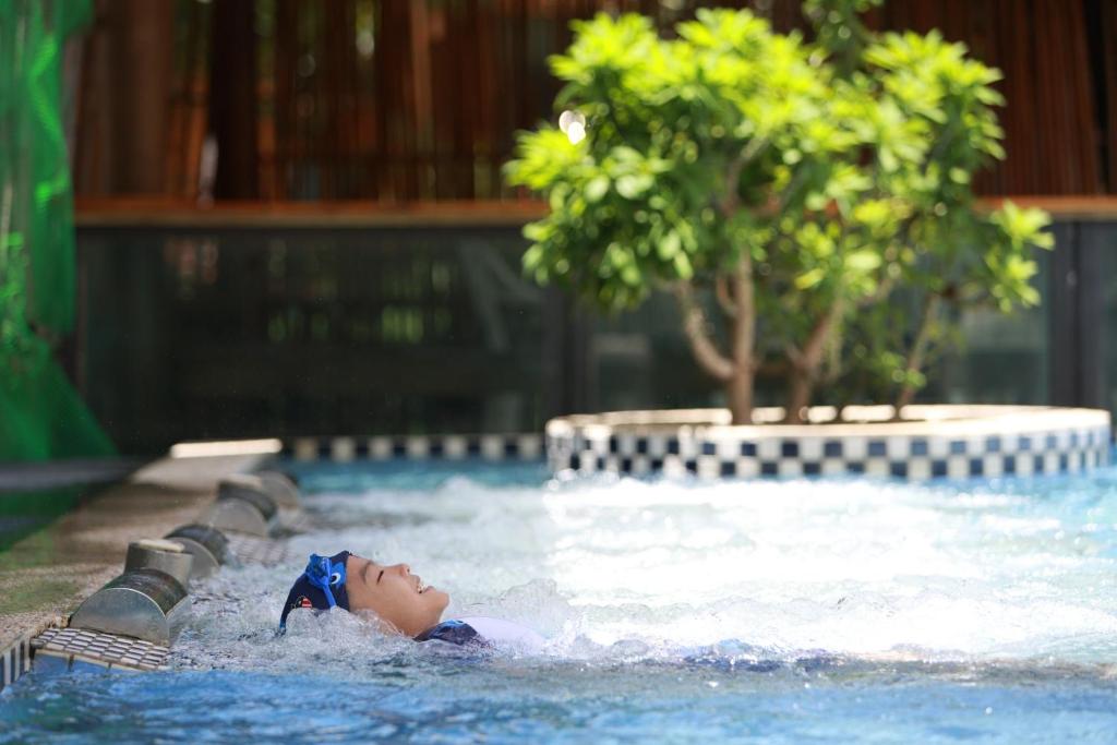 车城牡丹风情温泉行馆 的儿童在树荫游泳池游泳