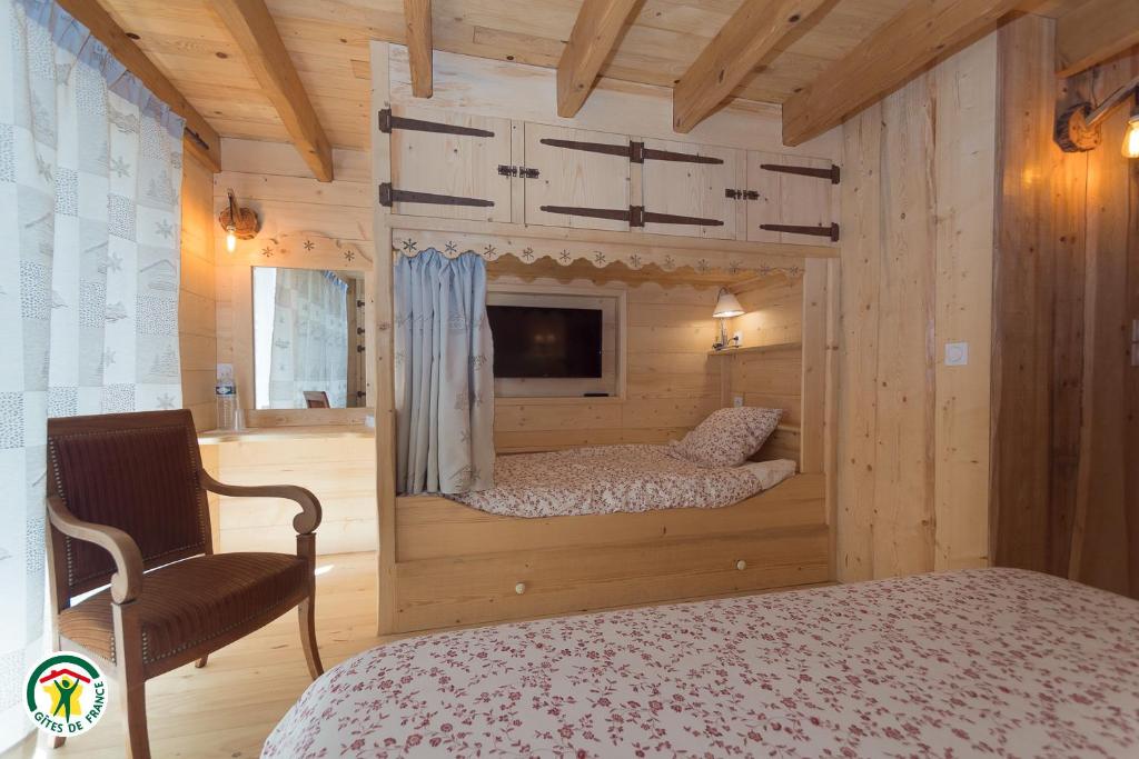 圣拉提尔Chalet le Clos de l'Orme的一间卧室配有一张床、一台电视和一把椅子