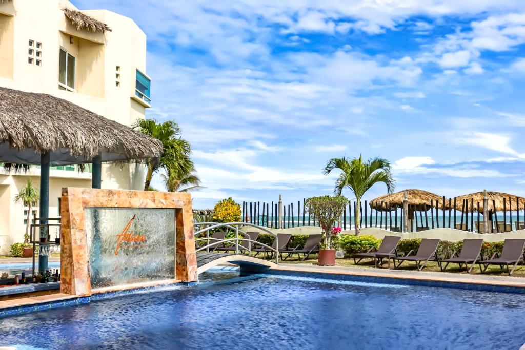 查察拉卡斯Artisan Family Hotels and Resort Collection Playa Esmeralda的度假村的游泳池,配有椅子和遮阳伞