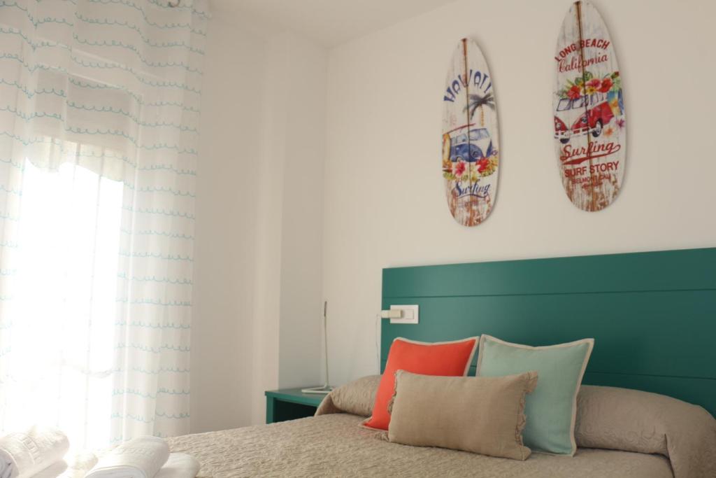 托莱多Apartamentos Homelife Roca Tarpeya的卧室配有一张床,墙上设有两个冲浪板