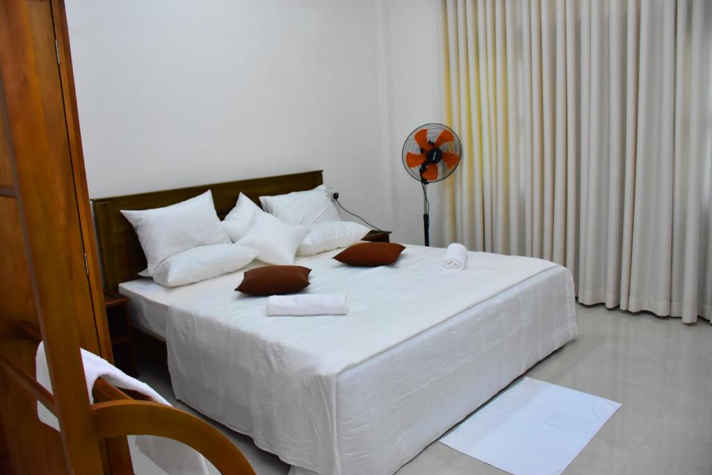 埃拉Ella, Nine Arch Holiday Resort的一间卧室配有一张带白色床单的床和风扇