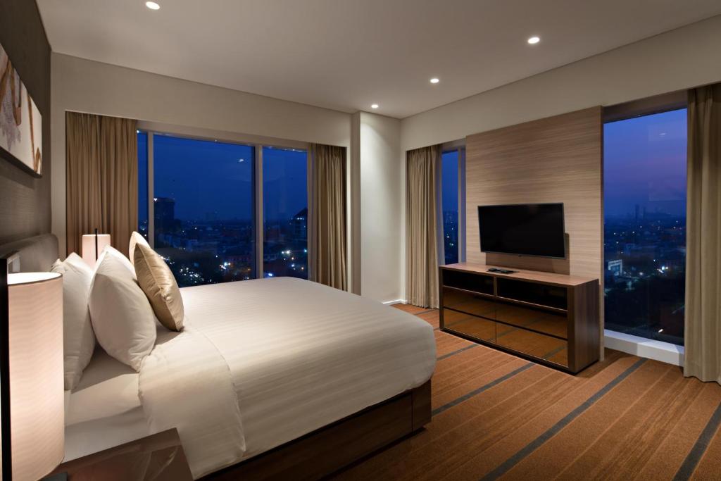 泗水Oakwood Hotel & Residence Surabaya的一间卧室配有一张大床和电视