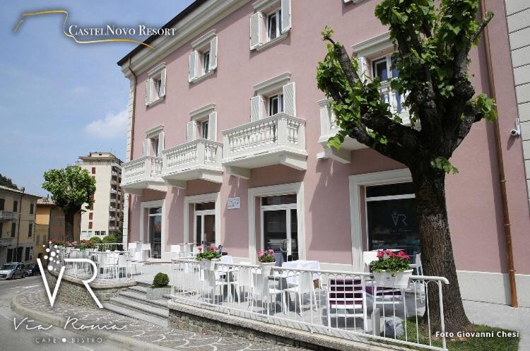 蒙蒂新堡Castelnovo Resort的前面有白色椅子的粉红色建筑
