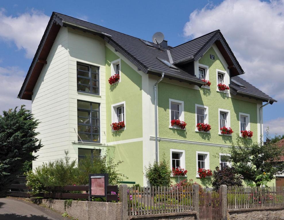巴特亚历山大斯巴德Landhaus Bruckner的绿色白色的房子,窗户上装有红色的鲜花