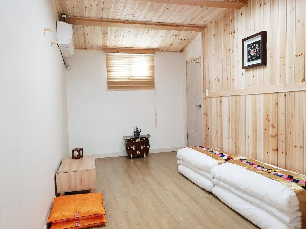 江陵市Dal Garam Guesthouse的一间设有两张白色床铺的客房,房间拥有木墙
