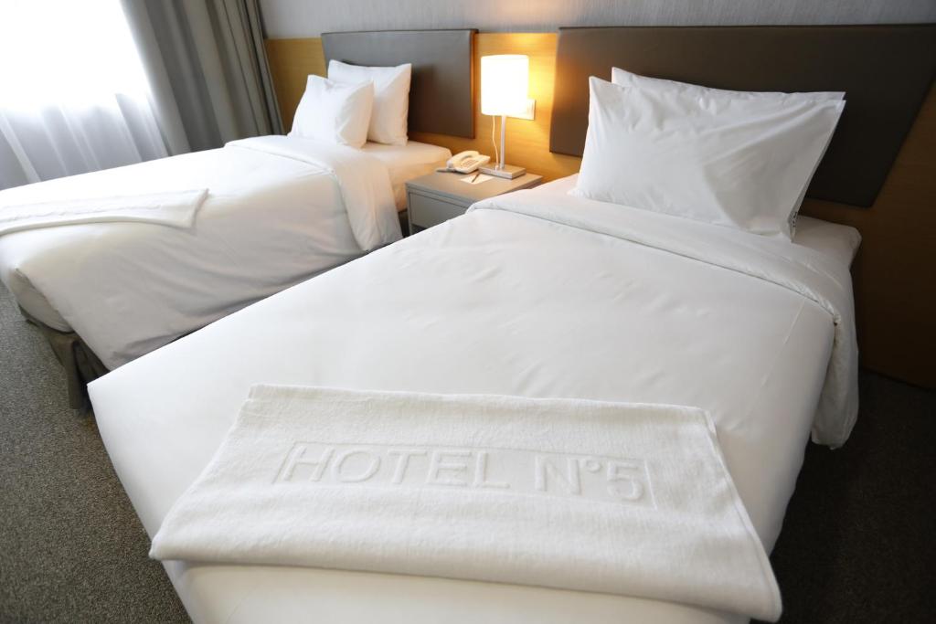哥打京那巴鲁Hotel N°5的两张位于酒店客房的床,上面有酒店标志